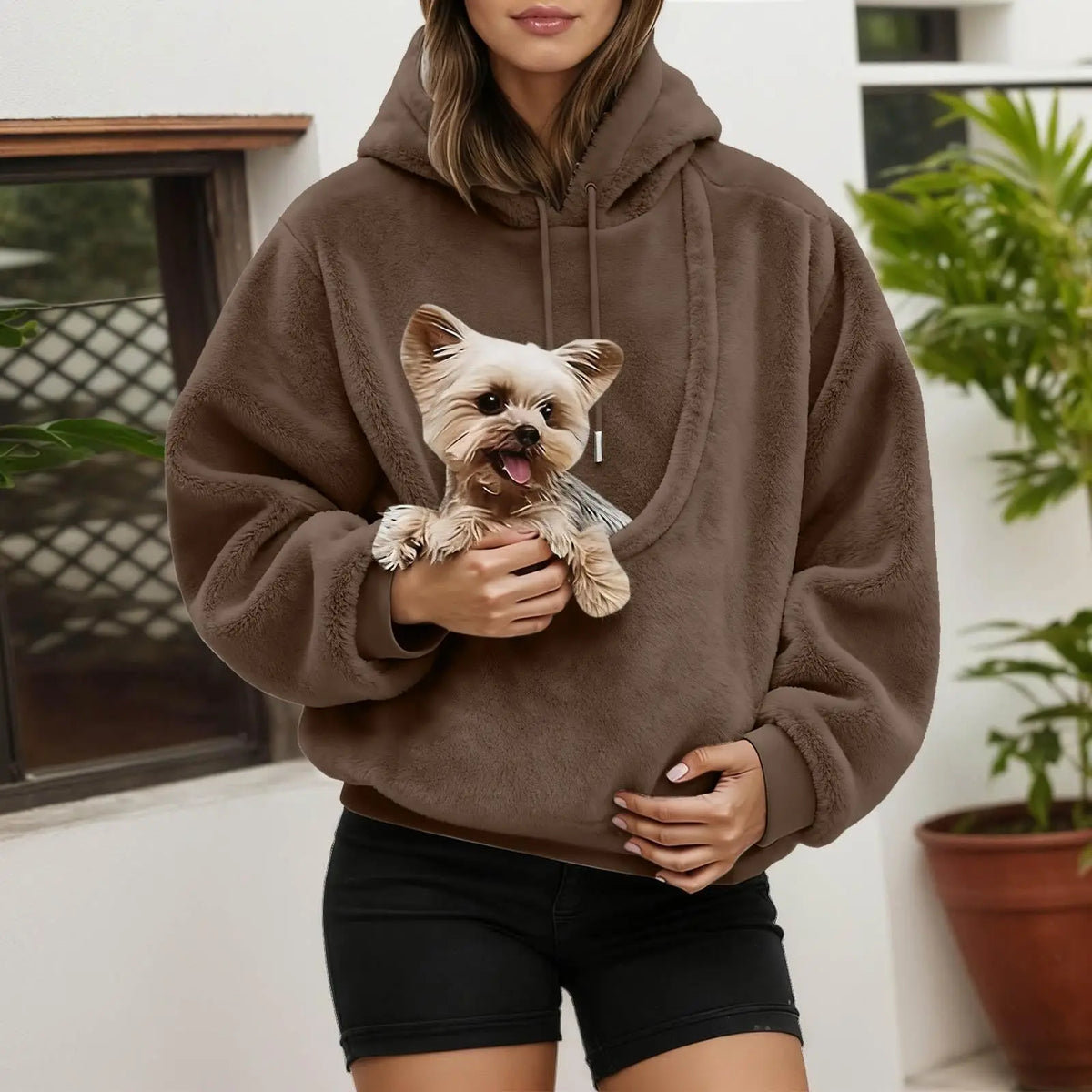 Mascota asomada en el bolsillo canguro de la sudadera marrón